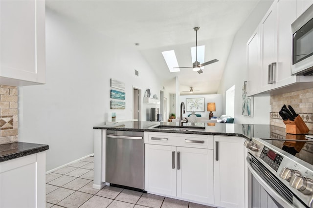 kitchen with sink, appliances with stainless steel finishes, dark stone countertops, white cabinets, and light tile patterned flooring