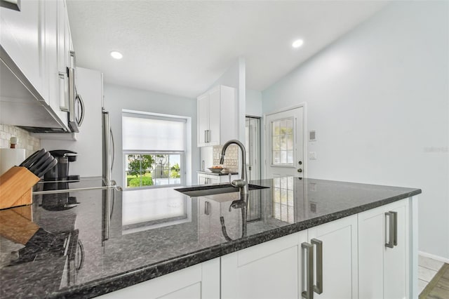 kitchen with dark stone counters, sink, decorative backsplash, and white cabinets