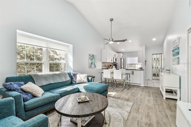 living room with ceiling fan, high vaulted ceiling, and light wood-type flooring