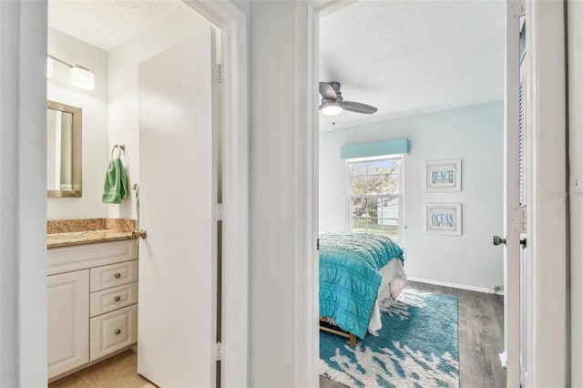 bathroom featuring hardwood / wood-style flooring, vanity, ceiling fan, and a textured ceiling