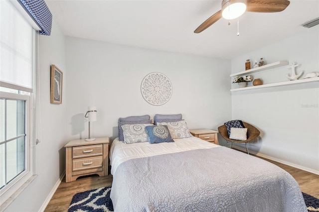 bedroom with multiple windows, ceiling fan, and dark hardwood / wood-style flooring