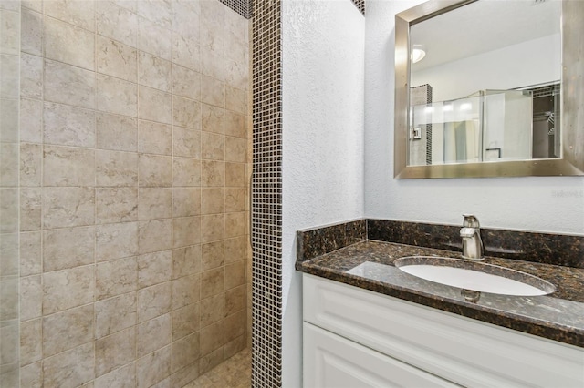 bathroom with vanity and a tile shower