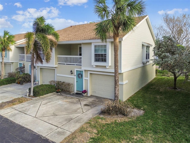 view of property featuring a garage, a balcony, and a front yard