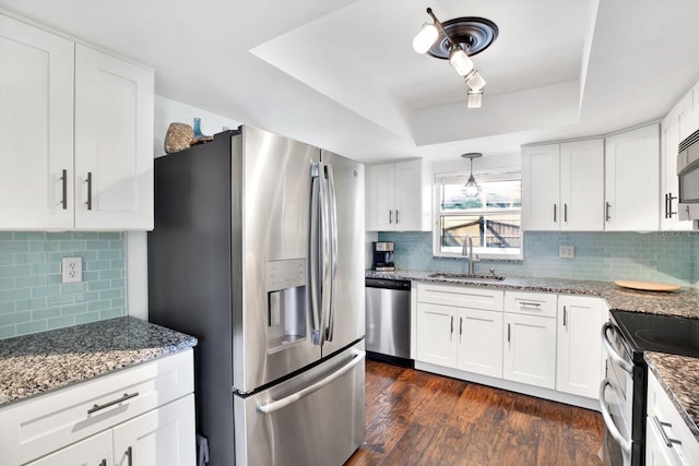 kitchen featuring stainless steel appliances, a tray ceiling, sink, and white cabinets