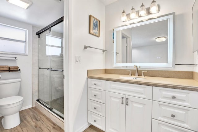 bathroom featuring hardwood / wood-style flooring, vanity, an enclosed shower, and toilet