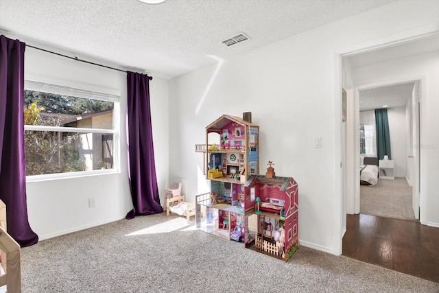 recreation room featuring a textured ceiling and carpet