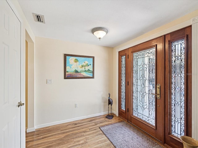 foyer entrance with light wood-style floors, baseboards, and visible vents