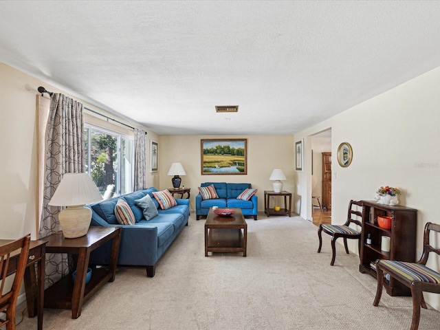 living room with visible vents, a textured ceiling, and light colored carpet