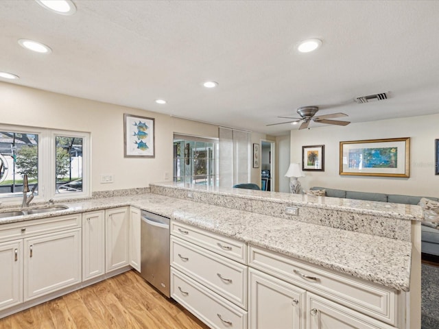 kitchen featuring a peninsula, a sink, visible vents, stainless steel dishwasher, and plenty of natural light