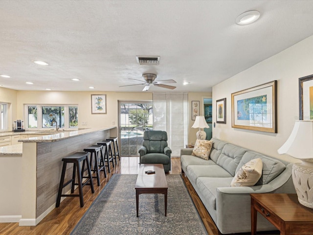 living room featuring visible vents, a ceiling fan, wood finished floors, a textured ceiling, and recessed lighting