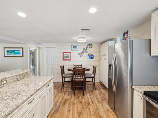 kitchen featuring white cabinets, light wood-style flooring, visible vents, and stainless steel refrigerator with ice dispenser