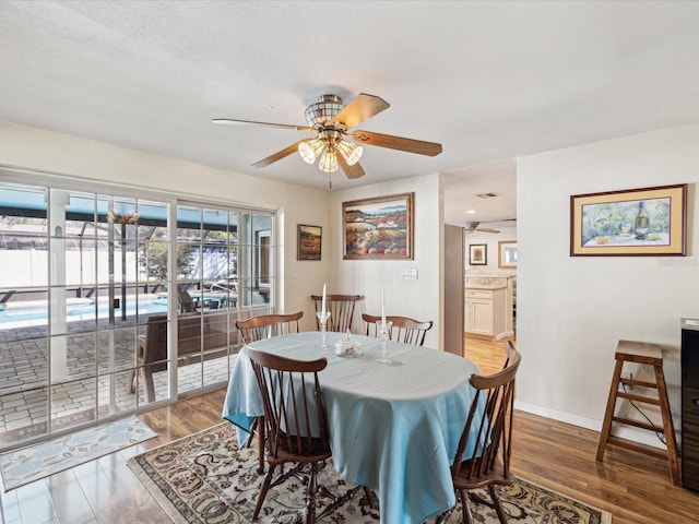 dining space featuring a ceiling fan, baseboards, and wood finished floors