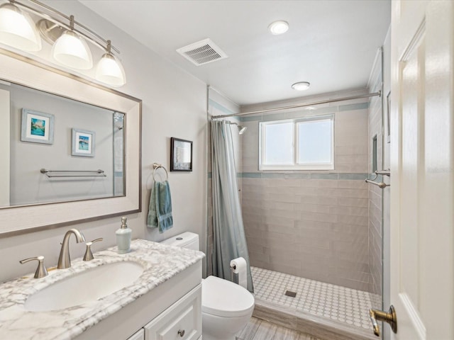 full bath with a stall shower, visible vents, vanity, and toilet