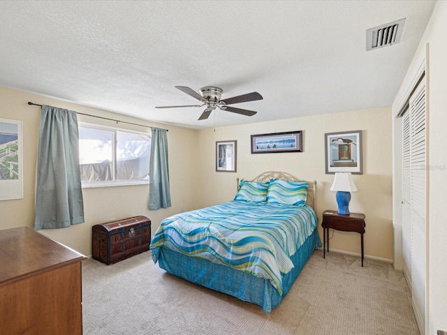 carpeted bedroom with a closet, visible vents, a ceiling fan, a textured ceiling, and baseboards