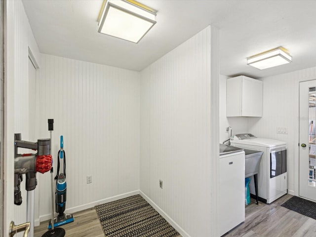 laundry area featuring light wood-type flooring, cabinet space, independent washer and dryer, and baseboards