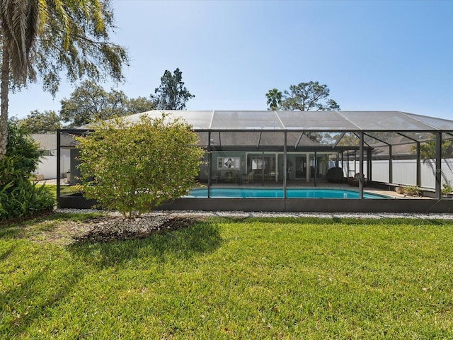 back of property with an outdoor pool, a yard, and a lanai