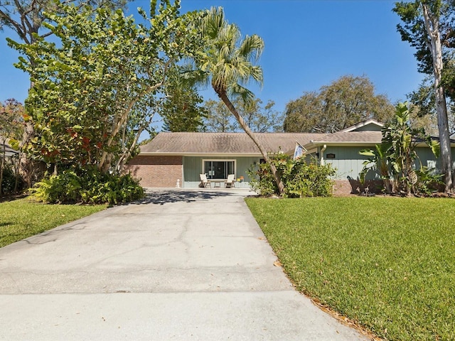 single story home featuring driveway, a front lawn, and brick siding