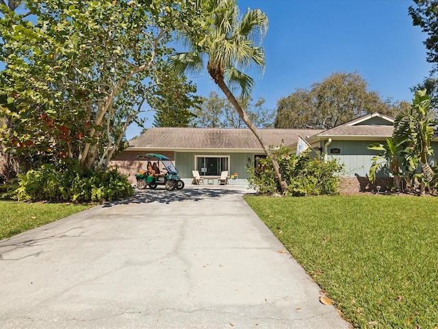 single story home featuring concrete driveway and a front lawn