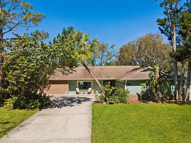 view of front of house with brick siding, concrete driveway, and a front yard