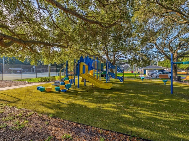 community play area with a tennis court, a lawn, and fence