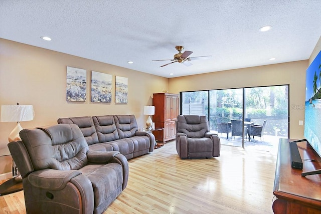 living room with ceiling fan, light hardwood / wood-style floors, and a textured ceiling