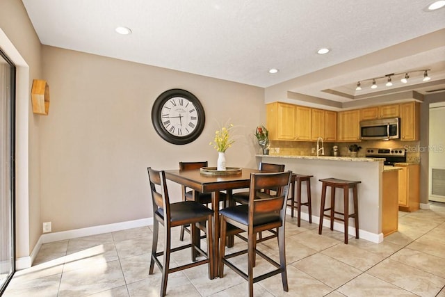 tiled dining area featuring sink, a tray ceiling, and a textured ceiling