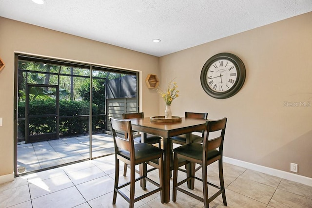 tiled dining space featuring a textured ceiling