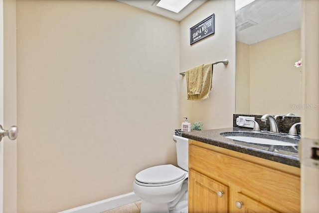 bathroom featuring vanity, tile patterned flooring, a skylight, and toilet