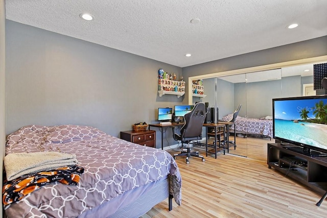 bedroom with a textured ceiling, light wood-type flooring, and a closet