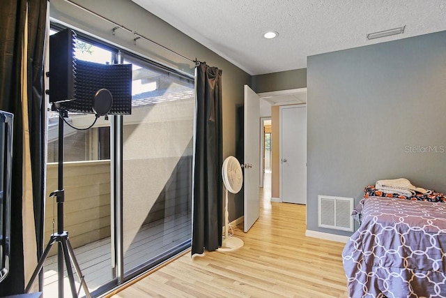 bedroom with light hardwood / wood-style flooring and a textured ceiling