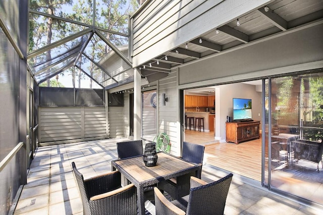 sunroom / solarium featuring beamed ceiling, rail lighting, and a wealth of natural light