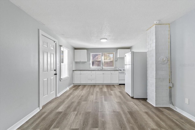 kitchen with white cabinetry, decorative backsplash, white fridge, stove, and light wood-type flooring