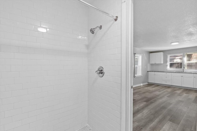 bathroom with hardwood / wood-style floors, tasteful backsplash, vanity, tiled shower, and a textured ceiling