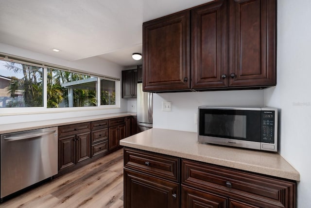 kitchen with stainless steel appliances, light hardwood / wood-style floors, and dark brown cabinets