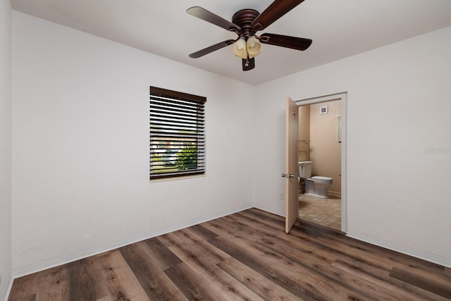 unfurnished bedroom with dark wood-type flooring, ensuite bath, and ceiling fan