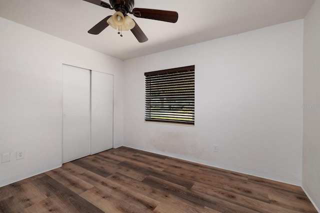 unfurnished bedroom with dark wood-type flooring, a closet, and ceiling fan