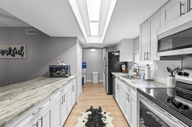 kitchen featuring white cabinetry, sink, light hardwood / wood-style flooring, and appliances with stainless steel finishes