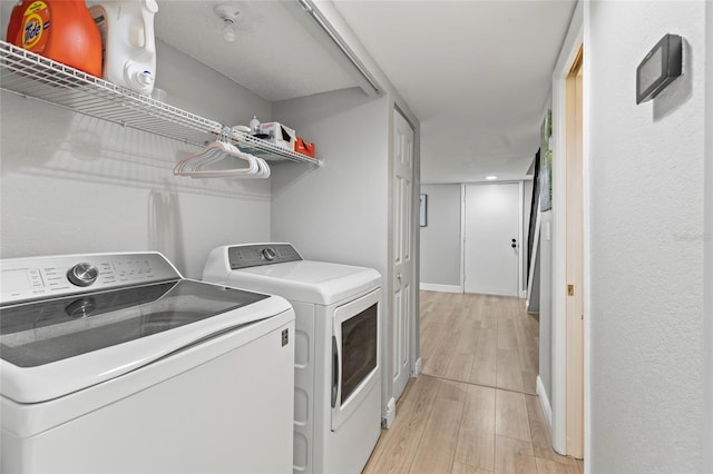 laundry area with washer and dryer and light hardwood / wood-style floors