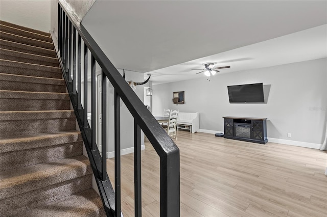 stairs with hardwood / wood-style flooring and ceiling fan