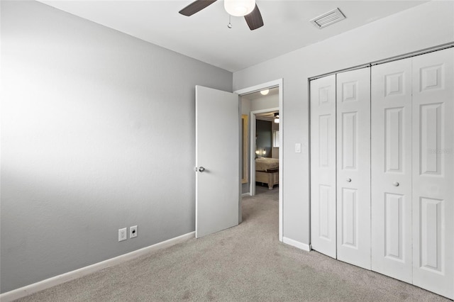 unfurnished bedroom with ceiling fan, light colored carpet, and a closet