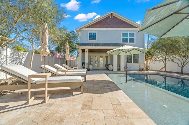 back of property with a fenced in pool, a patio, and french doors