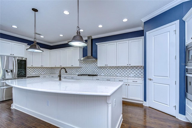 kitchen with stainless steel appliances, a kitchen island with sink, wall chimney range hood, and white cabinets