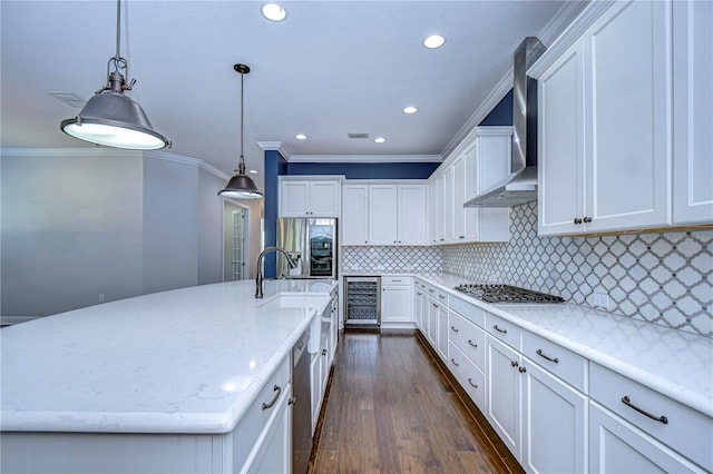 kitchen with pendant lighting, wall chimney range hood, stainless steel appliances, wine cooler, and a large island with sink