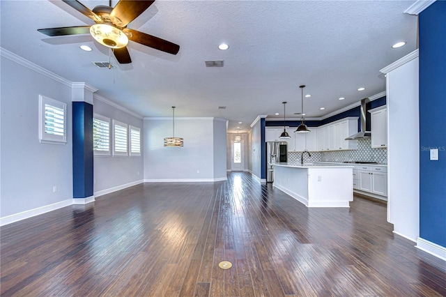 unfurnished living room with sink, ceiling fan, crown molding, dark wood-type flooring, and a textured ceiling