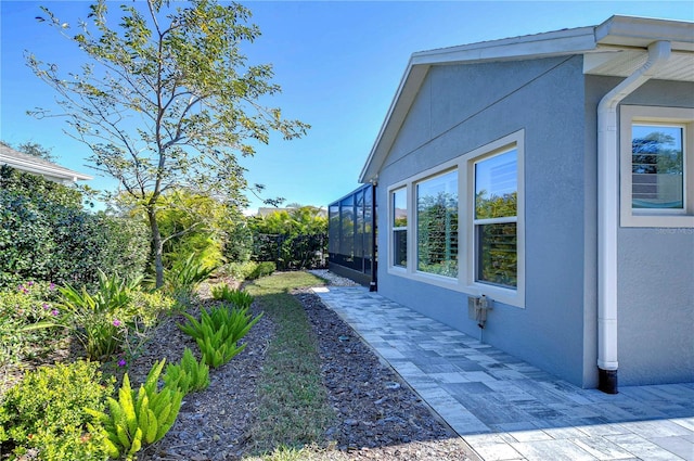 view of side of property with a lanai and a patio area