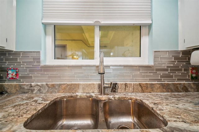 room details featuring sink, backsplash, and white cabinets