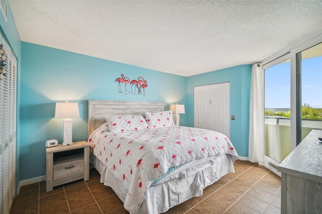 tiled bedroom featuring access to outside, a textured ceiling, and a closet