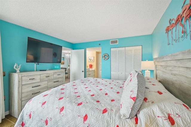 tiled bedroom featuring ensuite bath, a closet, and a textured ceiling