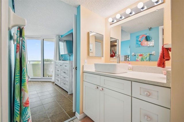 bathroom featuring a shower, expansive windows, vanity, tile patterned floors, and a textured ceiling