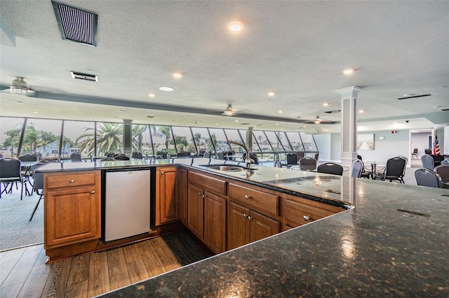 kitchen with sink, refrigerator, decorative columns, a wealth of natural light, and dark hardwood / wood-style flooring